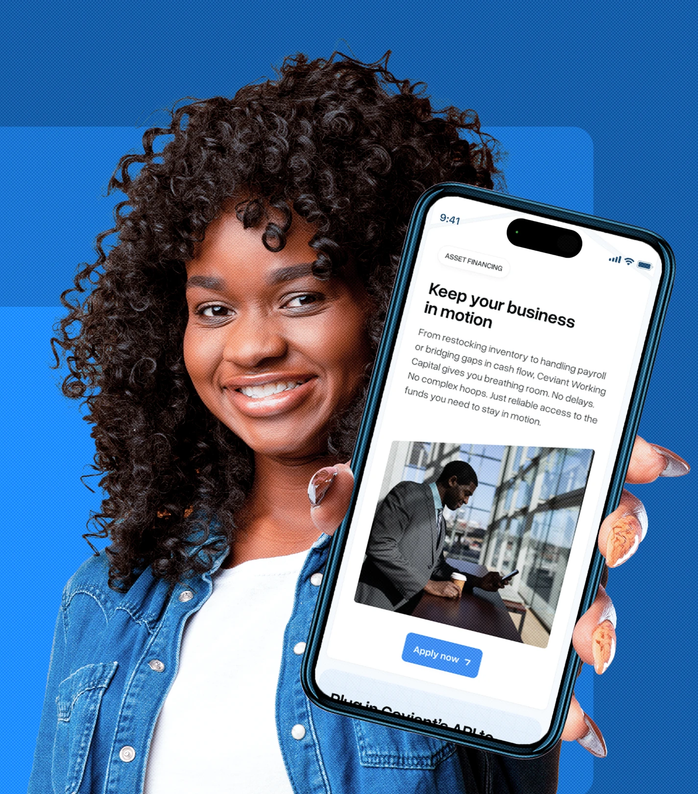 Smiling woman with curly hair holding a smartphone displaying a business financing app titled 'Keep your business in motion.'