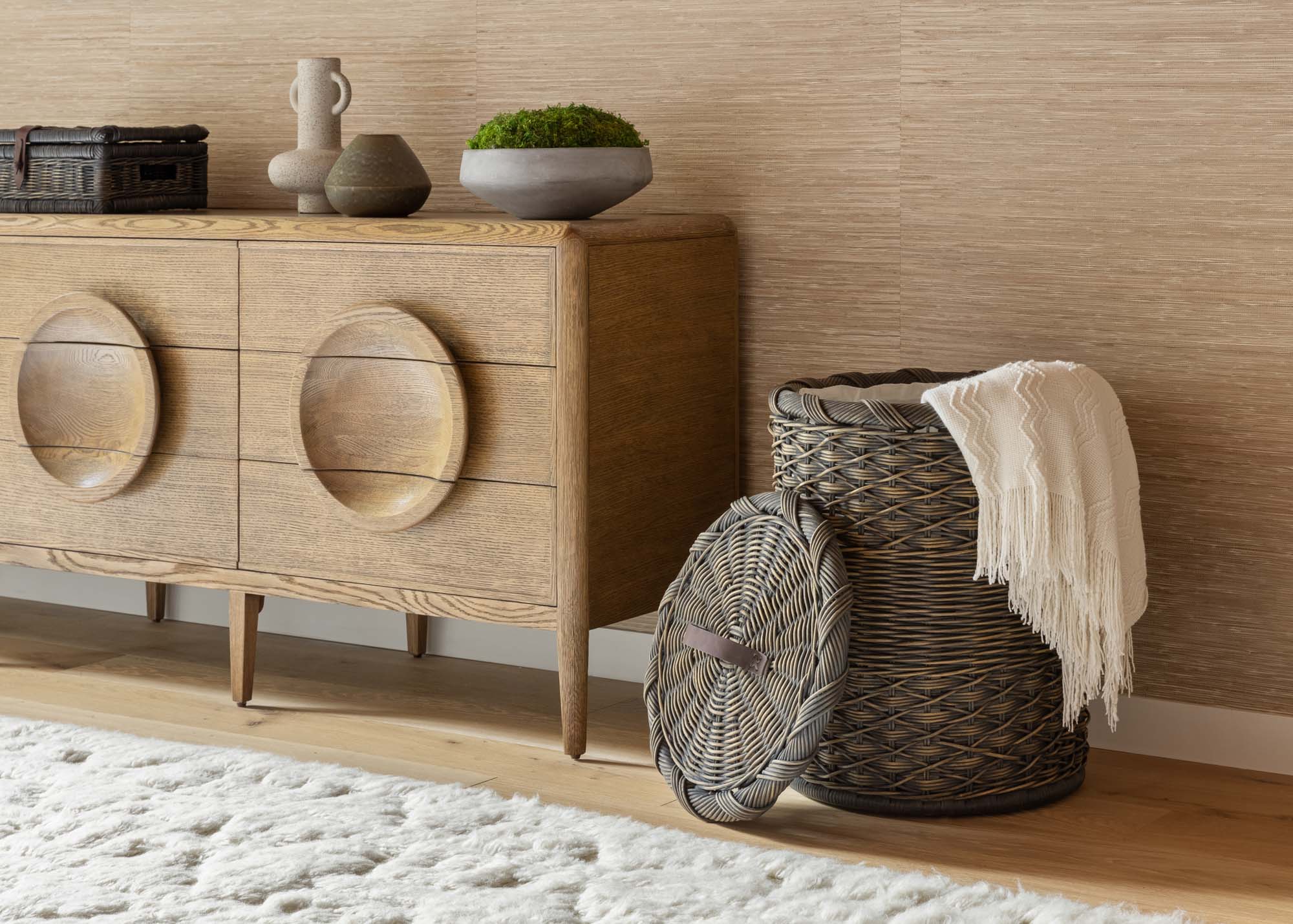 Woven rattan baskets and a cream throw blanket styled beside a wood console table.