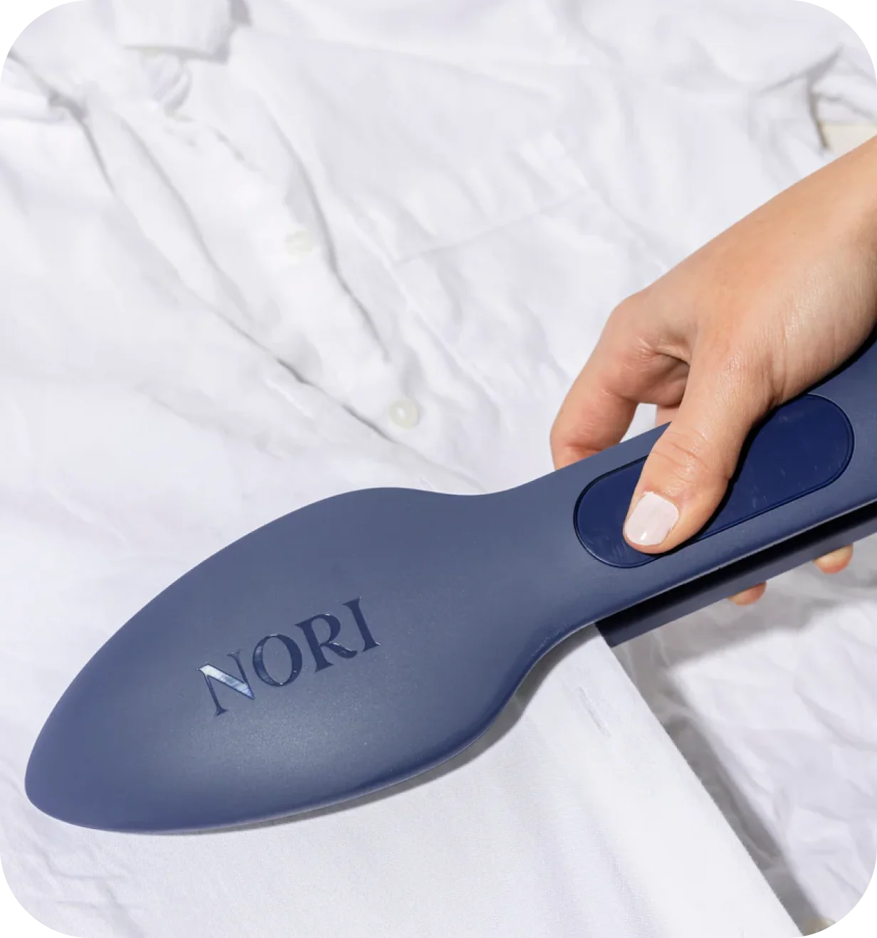 Hand holding a NORI handheld garment steamer against a white dress shirt.