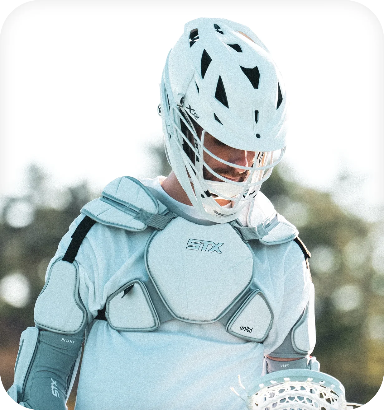 Lacrosse Unlimited lifestyle photo of a lacrosse player in a white helmet and protective pads.
