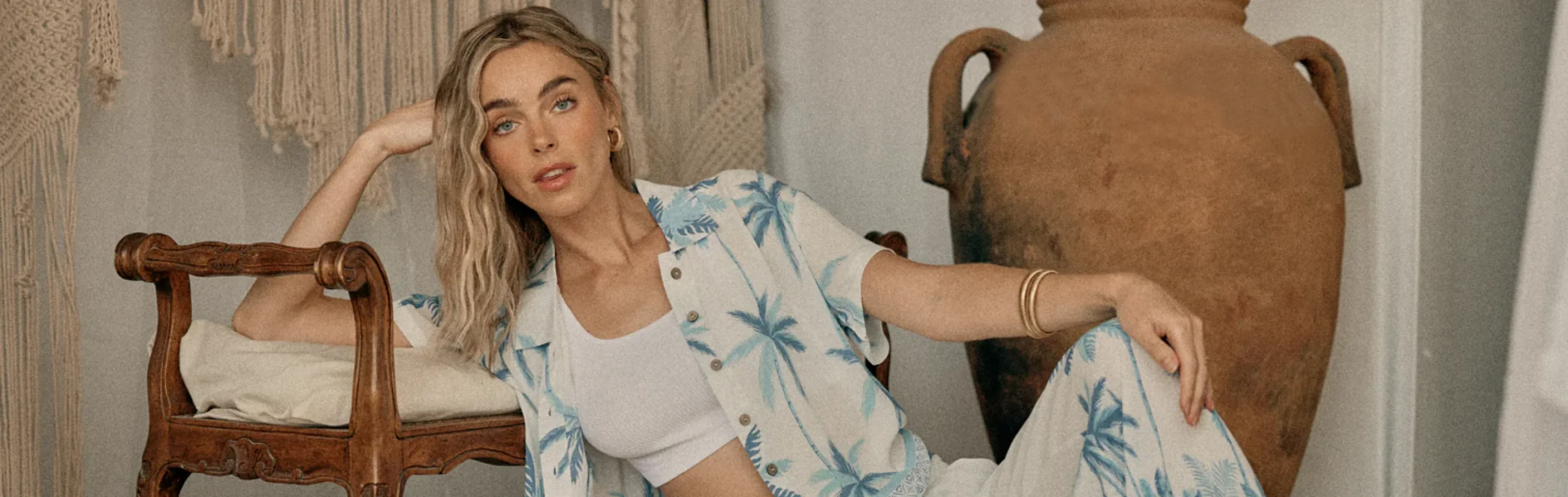 Model in a Vintage Havana palm-print shirt lounging beside a large terracotta urn.