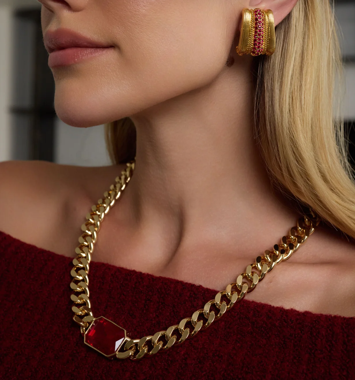 Kenneth Jay Lane lifestyle photo of a model wearing a gold chain necklace with red crystal and matching earring.
