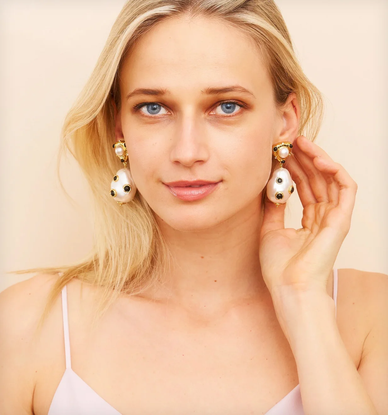 Kenneth Jay Lane lifestyle photo of a model wearing gold and pearl drop earrings.