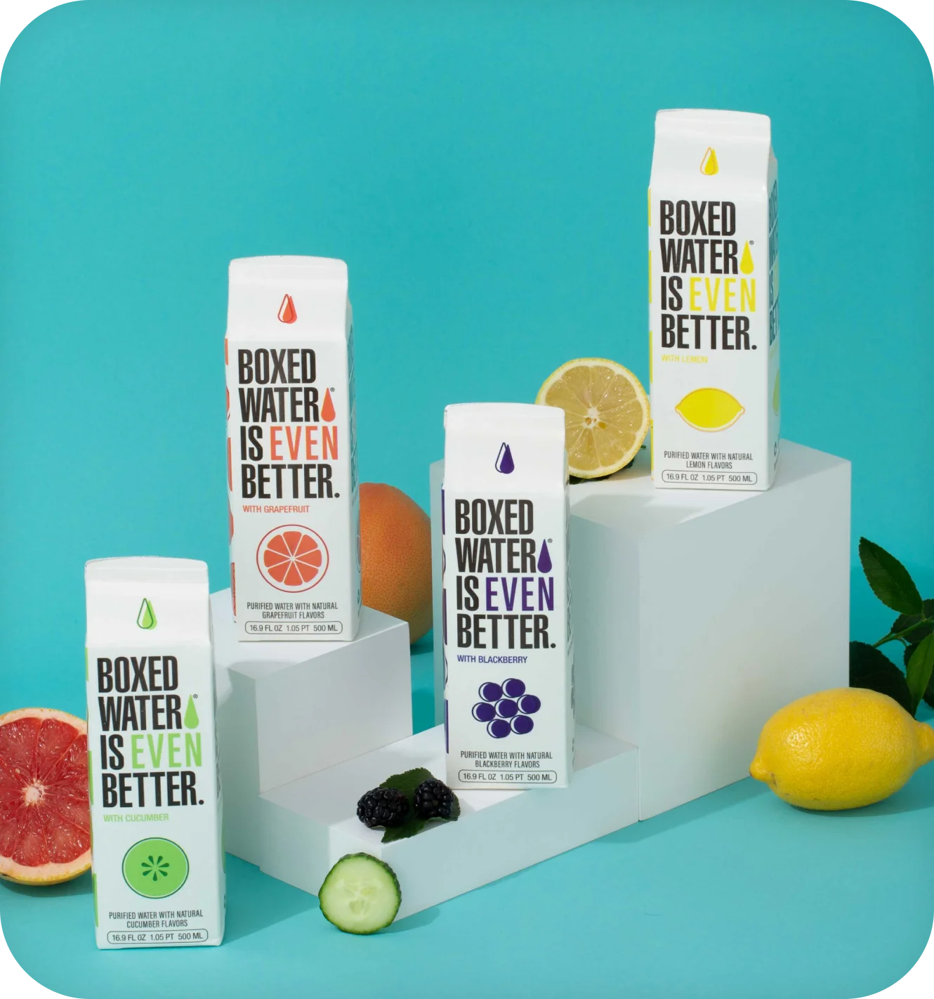 Boxed Water flavored cartons styled with fresh fruit against a teal backdrop.