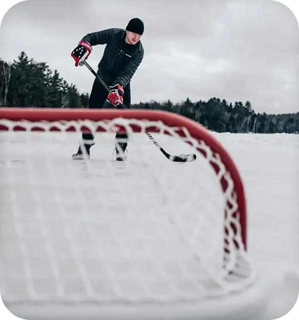 Winnwell lifestyle photo of a hockey player shooting toward a net on an outdoor pond rink.