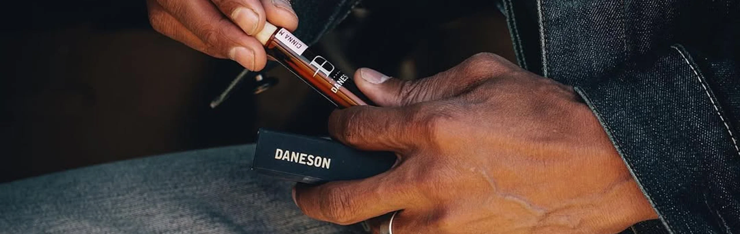 Hands sliding a Daneson cinnamon toothpick bottle out of its black box.