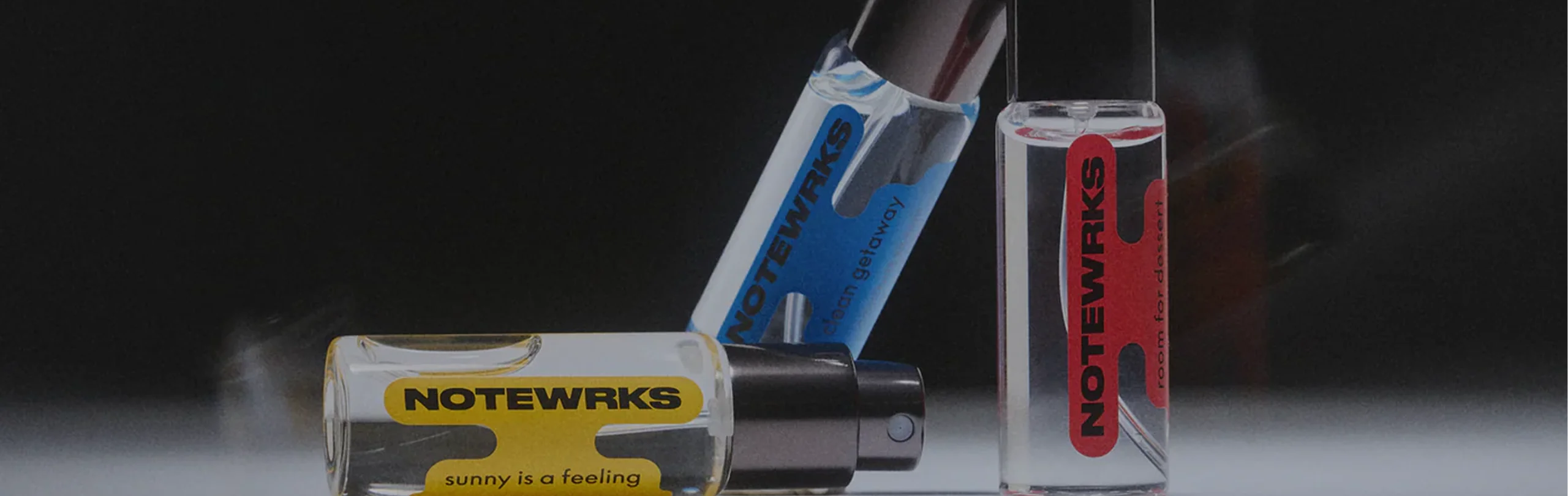 Three Snif NOTEWRKS fragrance vials with yellow, blue, and red labels on a dark background.