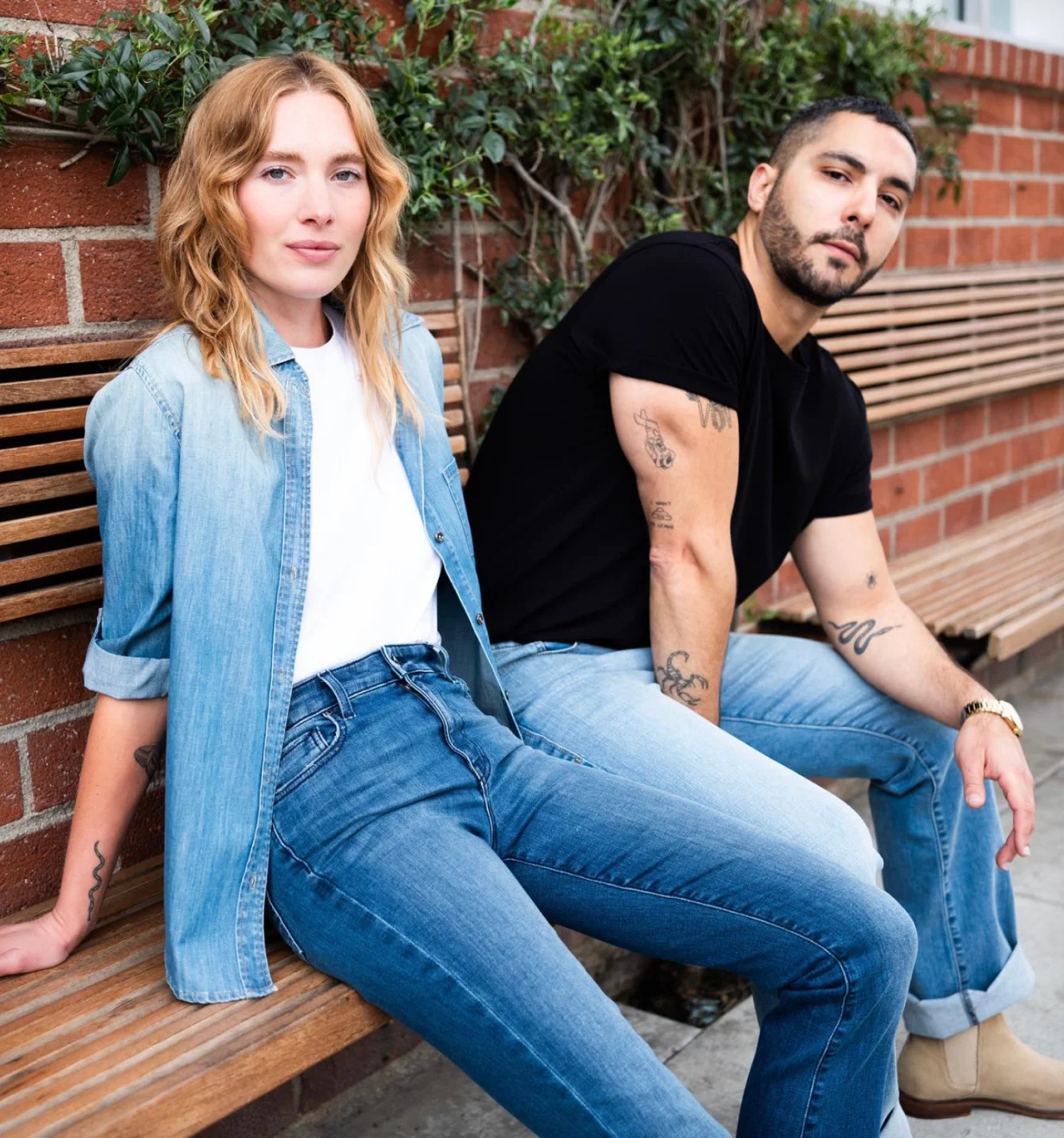 Fidelity Denim lifestyle photo of two models wearing jeans on a wooden bench.