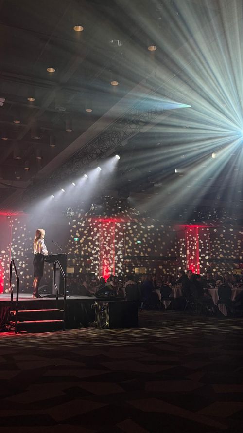 Linda on stage at a Gala, talking behind a podium