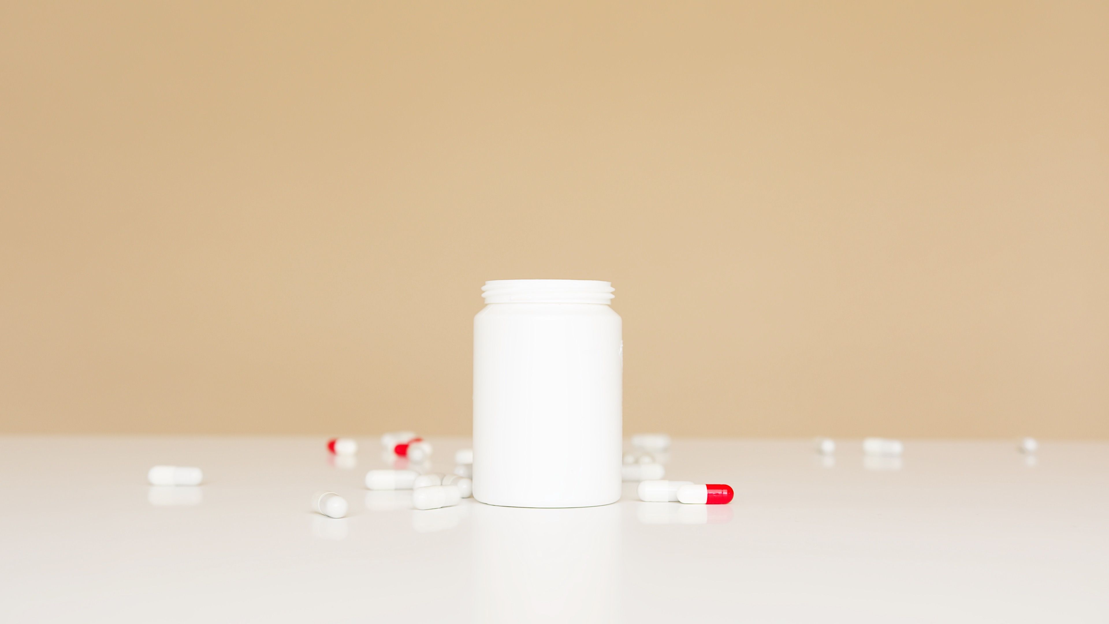 Open pill bottle with capsules scattered on a table