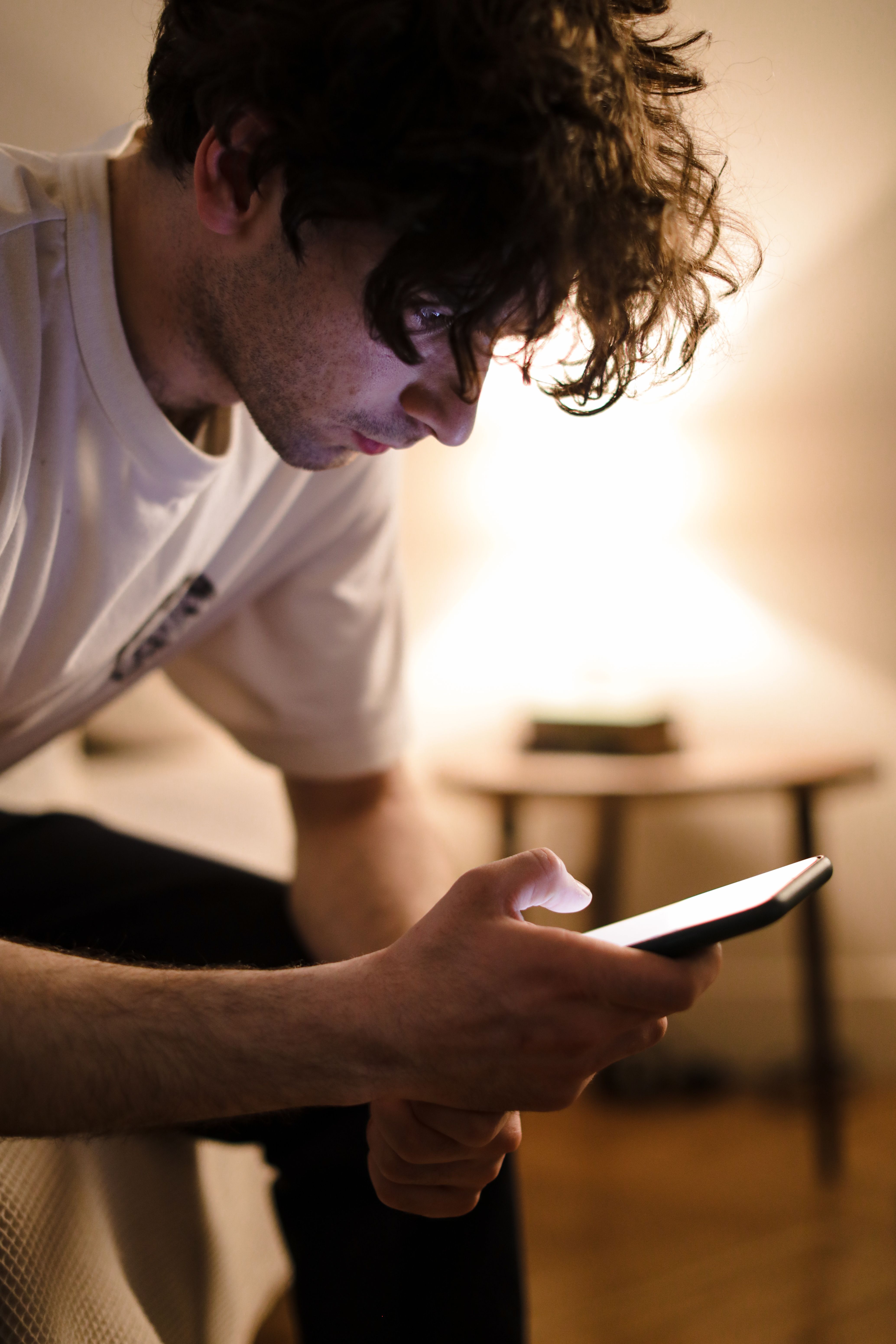 Man using his phone while sitting on a bed