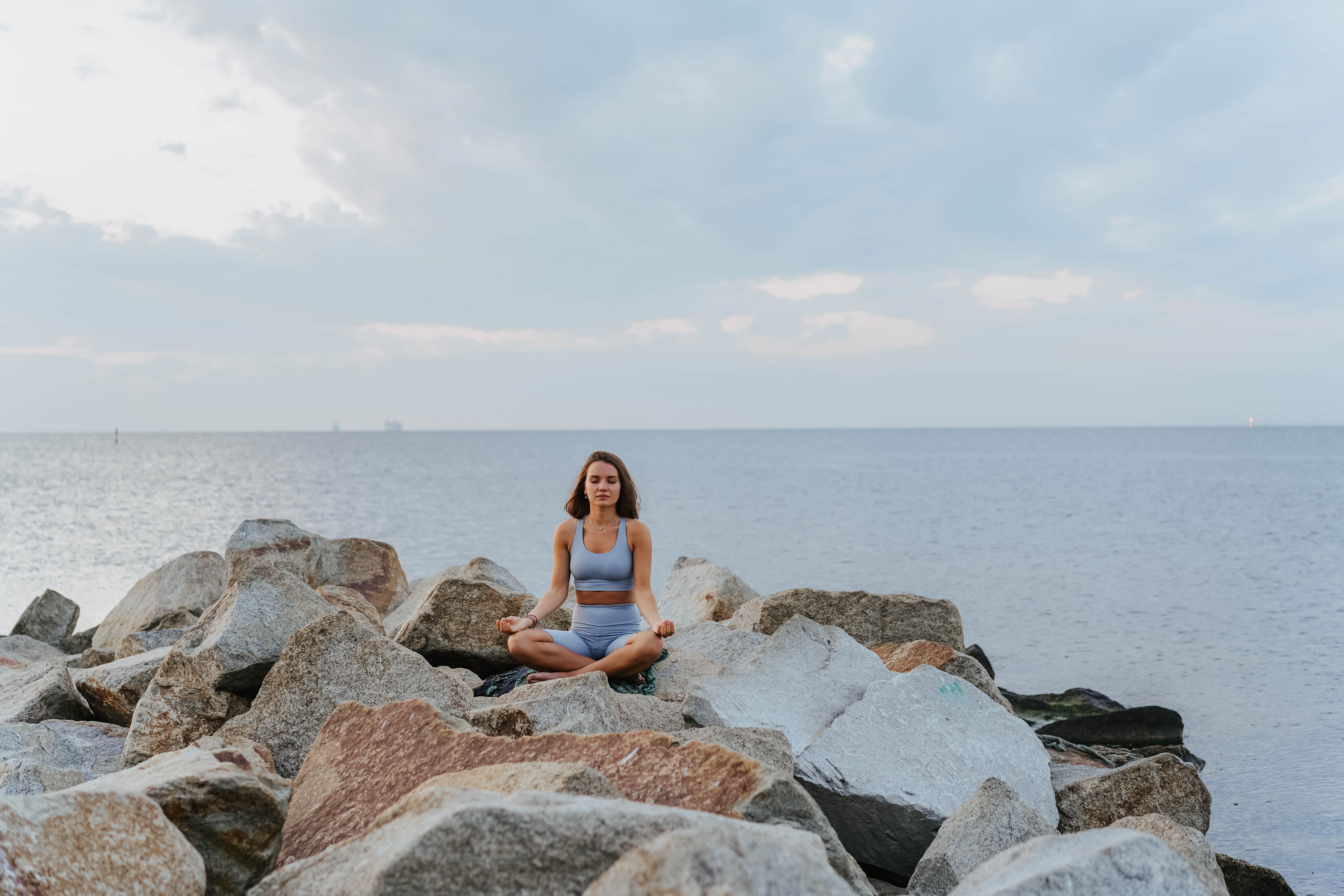 Woman meditating on rocks near the sea