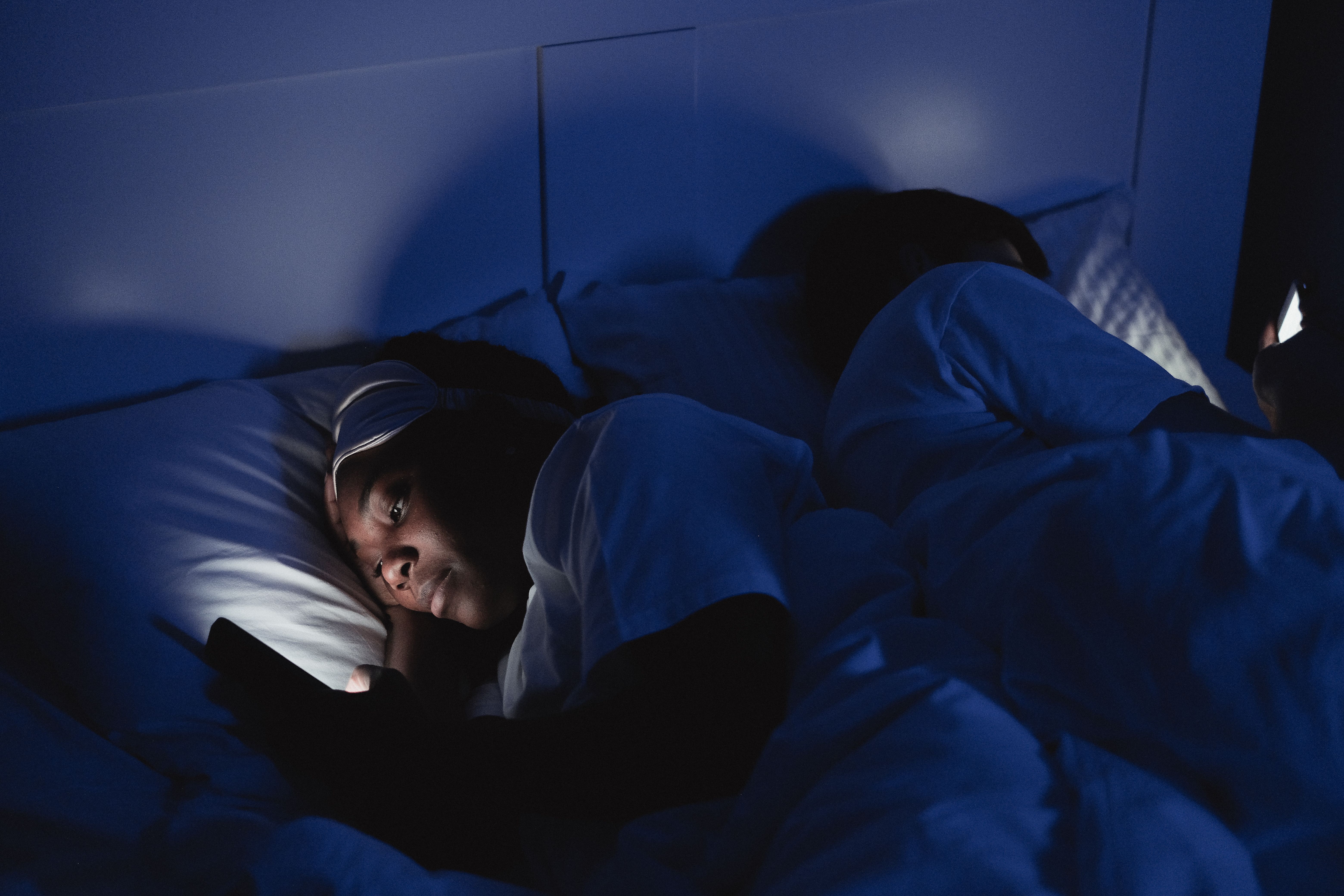 Person using a smartphone while lying in bed at night