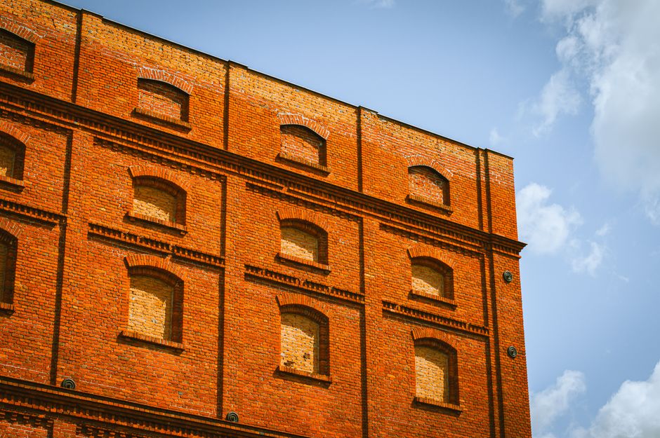 Low angle view of a historic red brick building in Łódź, Poland against a blue sky.