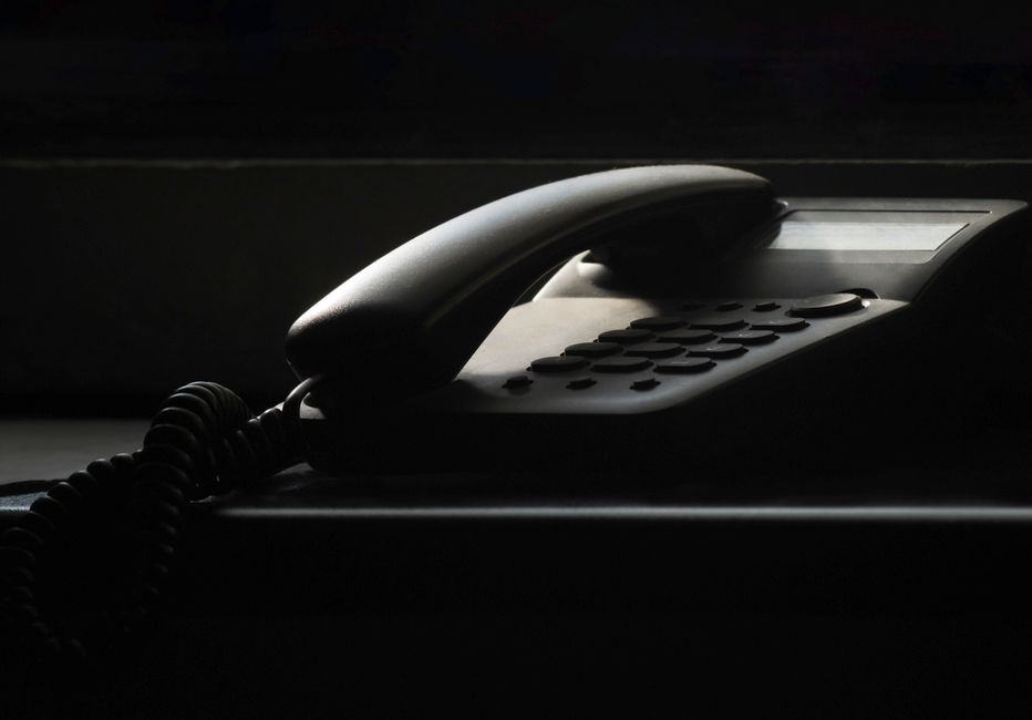 A close-up of a vintage landline phone in dramatic shadow lighting, evoking nostalgia.