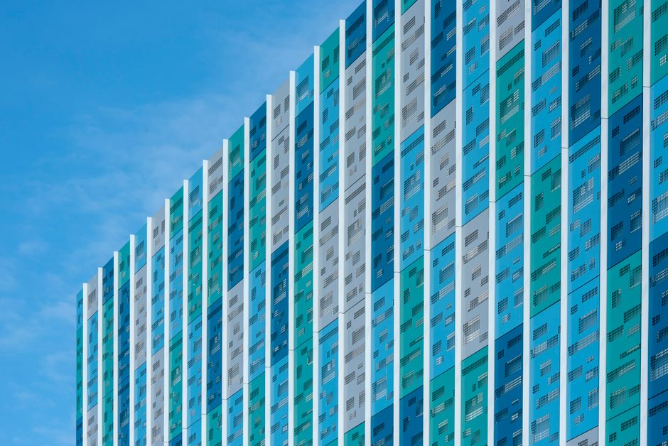 Vibrant geometric facade of a modern building with a blue sky backdrop, showcasing colorful abstract patterns.