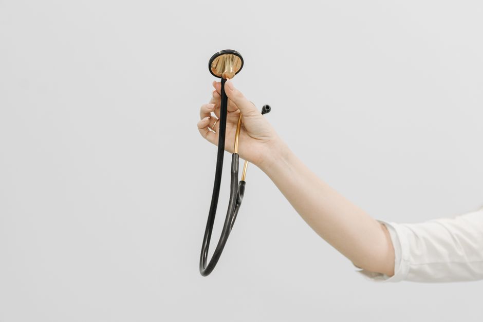 A hand holding a stethoscope, symbolizing medical care and healthcare on a white background.