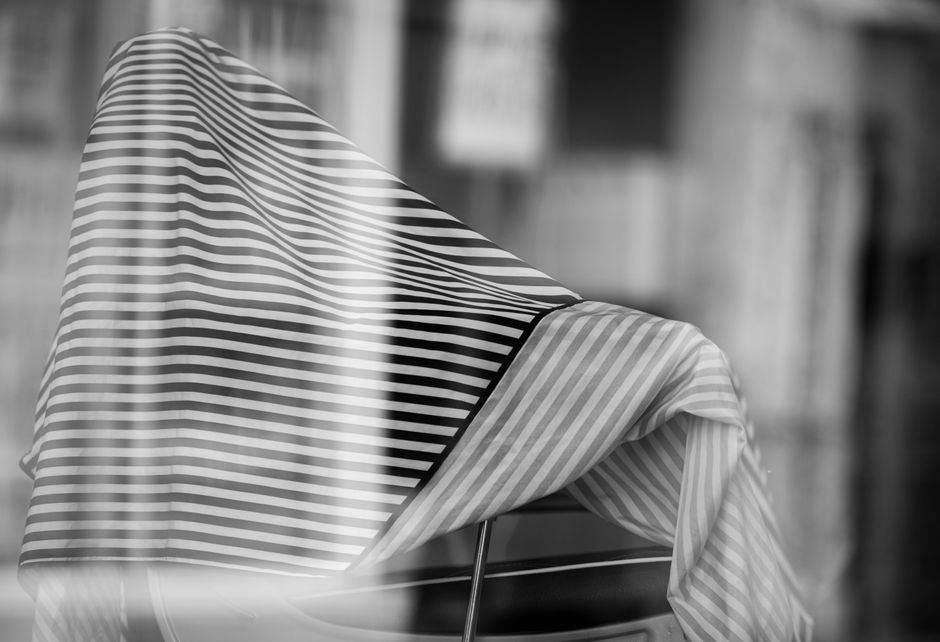 A monochrome image of a striped fabric draped over a chair with artistic blur.