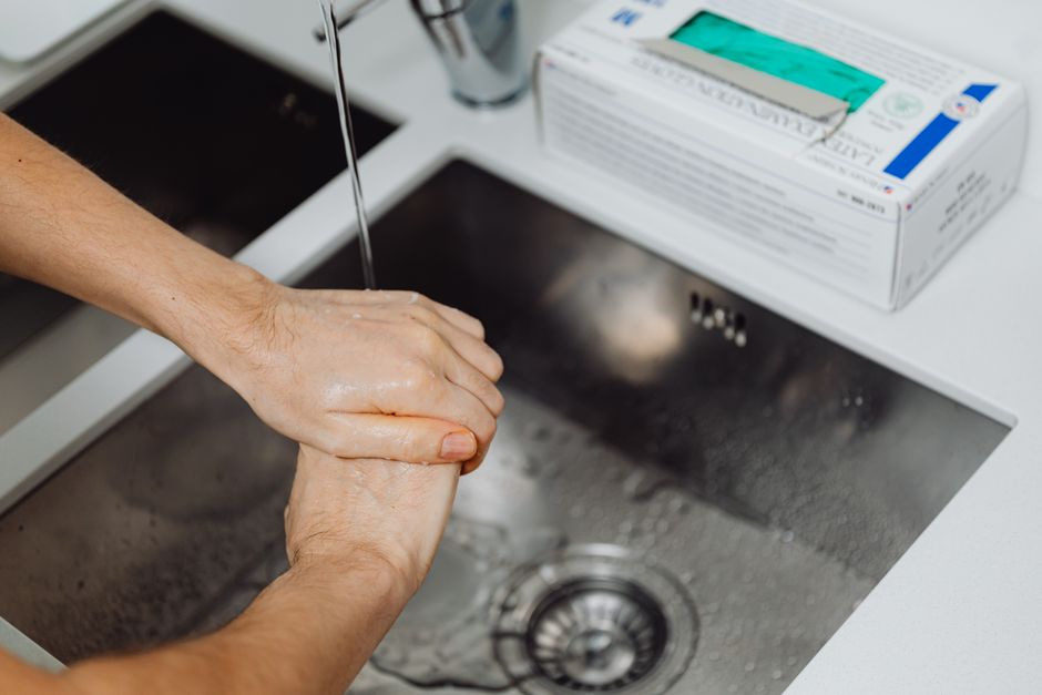 Detailed view of hands being washed under a tap, emphasizing hygiene and sanitation.