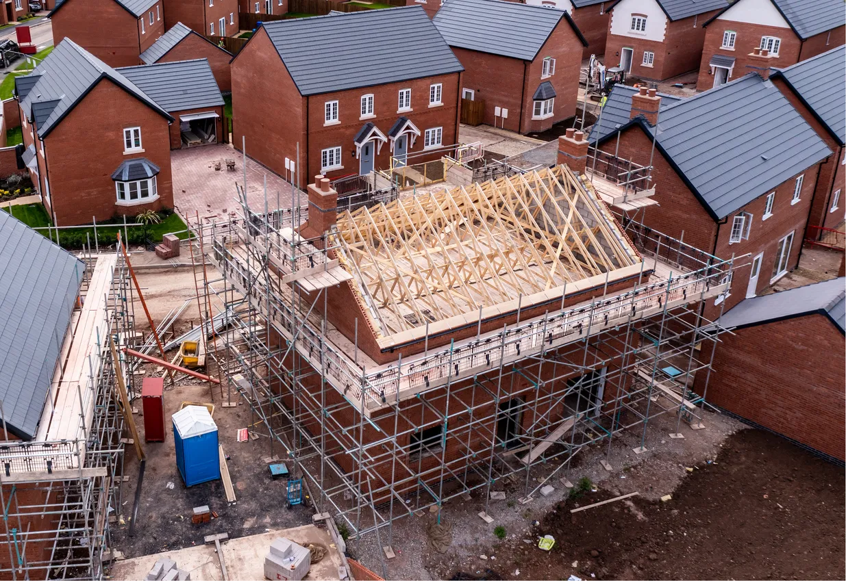 An aerial view of new build homes on a housing estate with the roof exposed and wooden rafters and beams showing