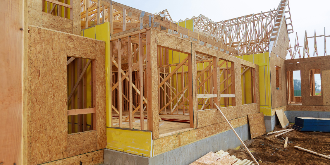Timber-framed house under construction on a building site.