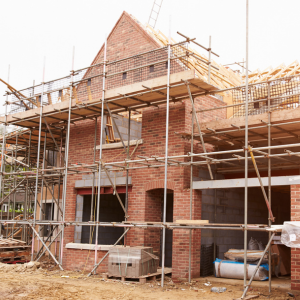 New brick housing development under construction, surrounded by scaffolding and building materials