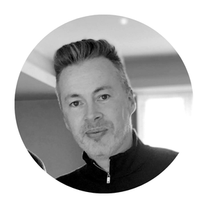 Portrait of a man with short grey hair wearing a dark zip-up top, shown in a circular profile photo.