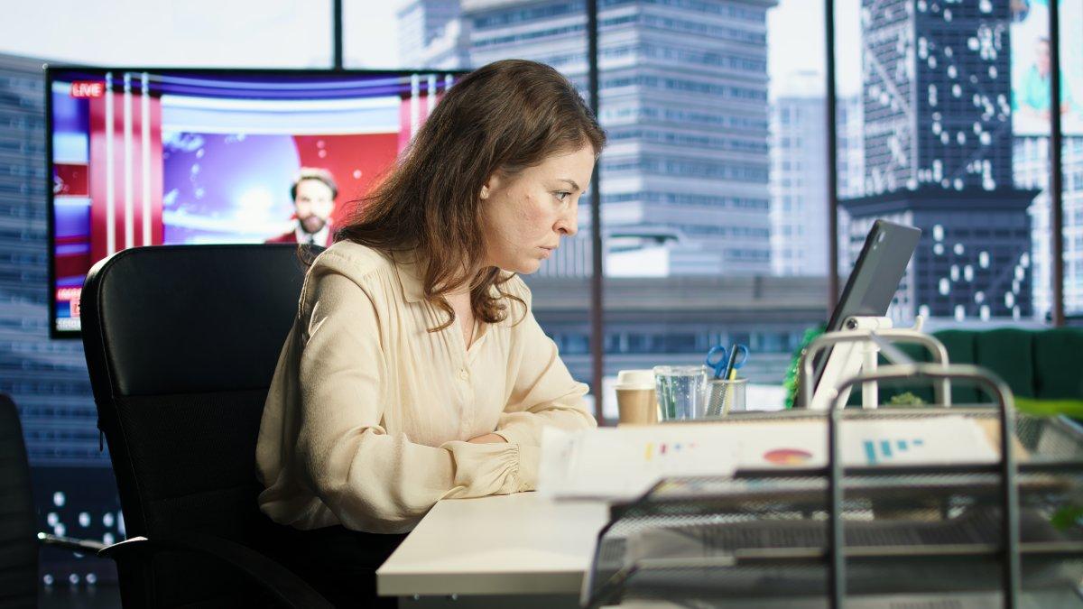"Journalist reviewing video footage on multiple screens to verify authenticity before broadcast"