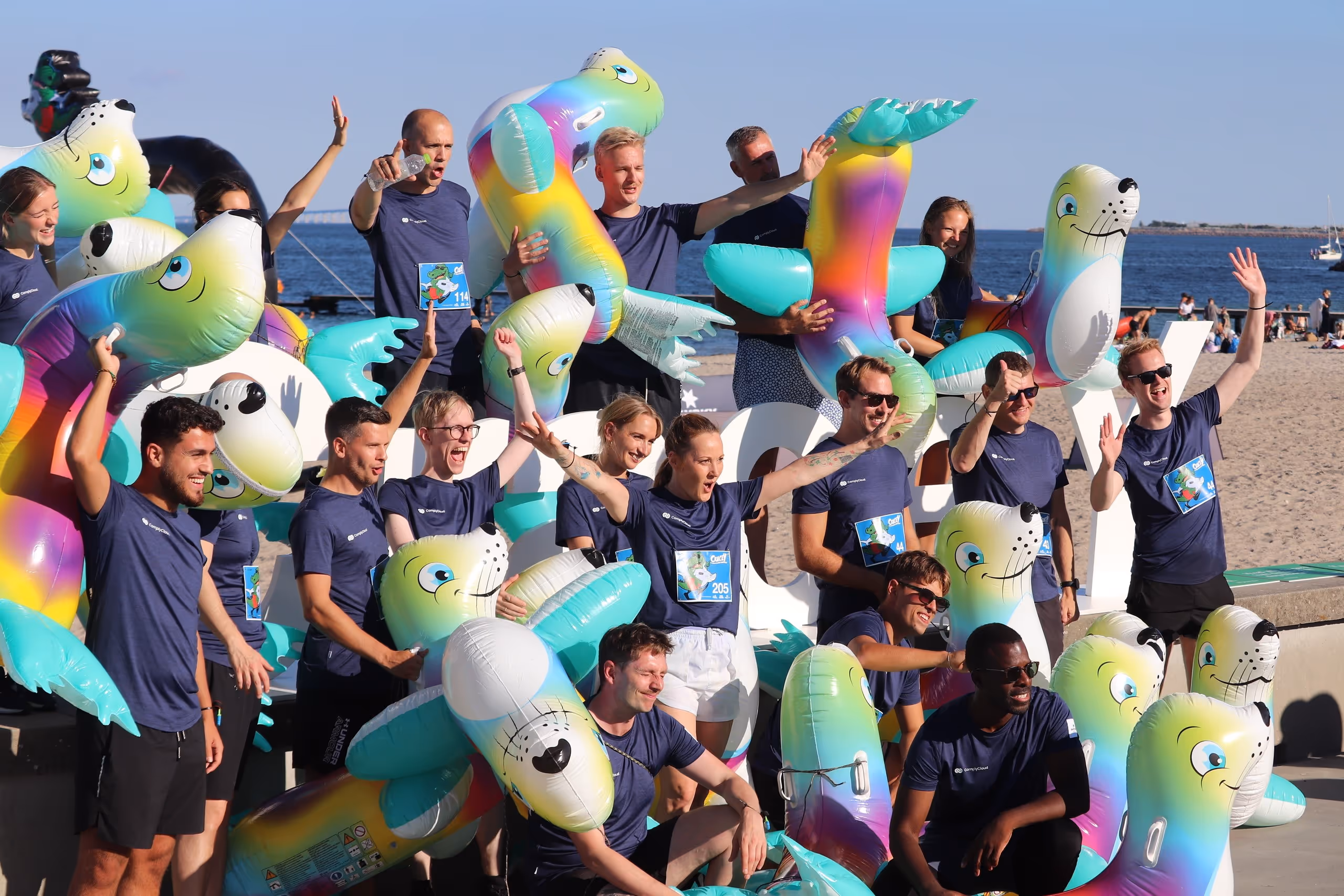 ComplyCloud-medarbejdere nyder en sjov teambuilding-dag på stranden med oppustelige figurer.
