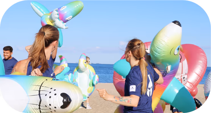 Team members enjoying a fun beach game with colorful inflatable seals.