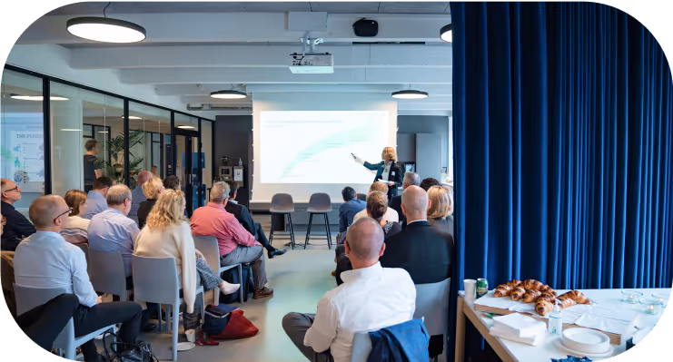 Compliance seminar with a speaker presenting to an engaged audience in a modern conference room.