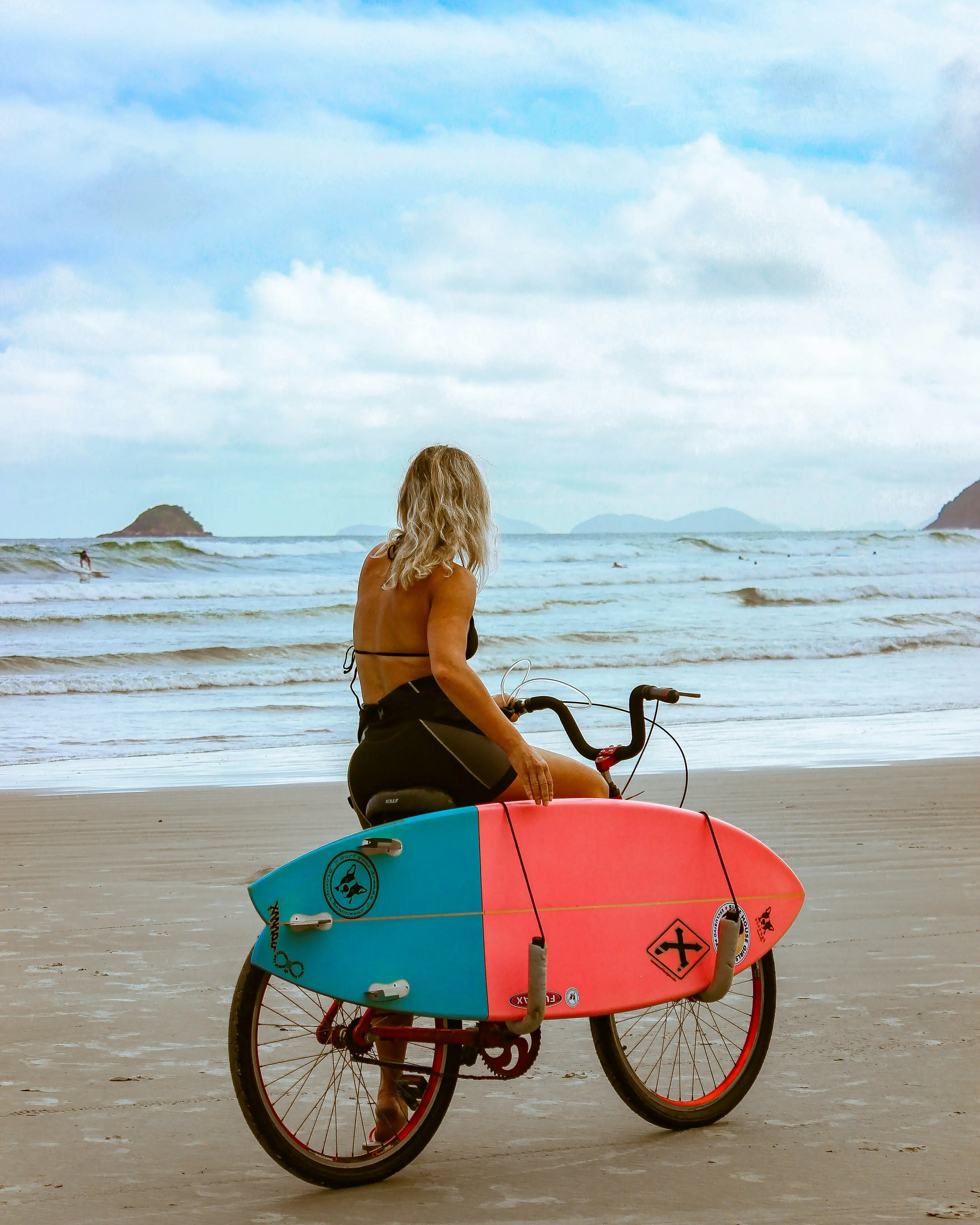 Surfer riding a bike on the beach