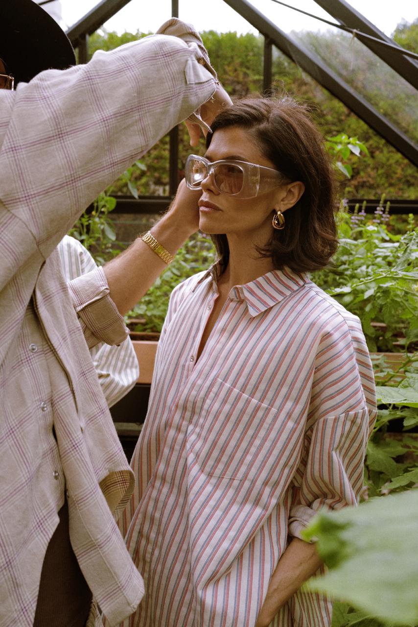 Woman in a solid amber shirt and trousers standing in a walk-in closet