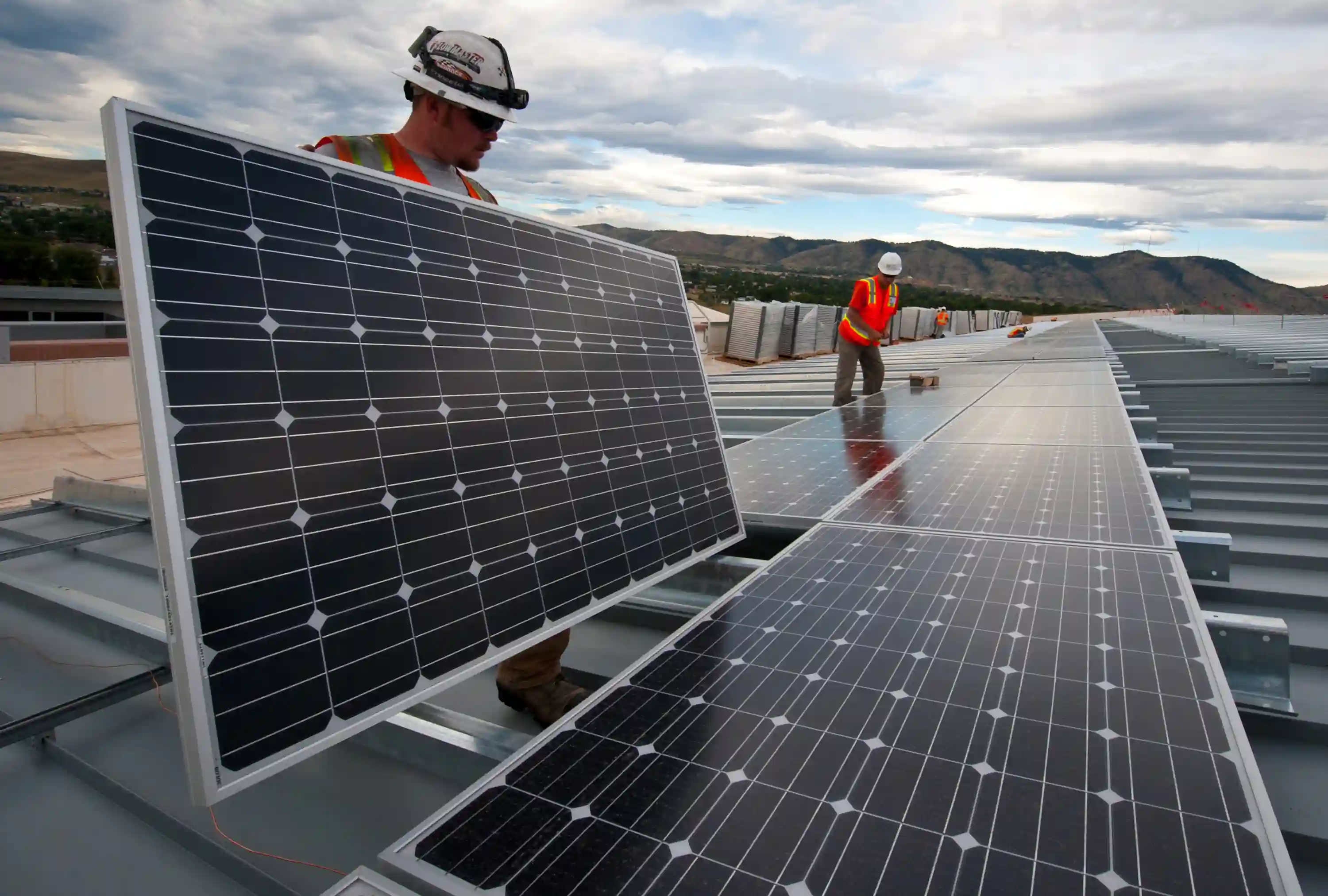 Montörer installerar solpaneler på ett stort plåttak