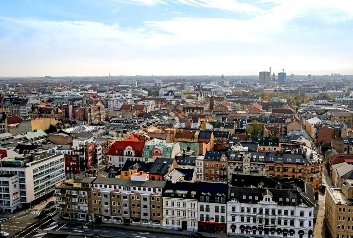 Flygvy över Malmö med täta stadskvarter och Öresund i bakgrunden.
