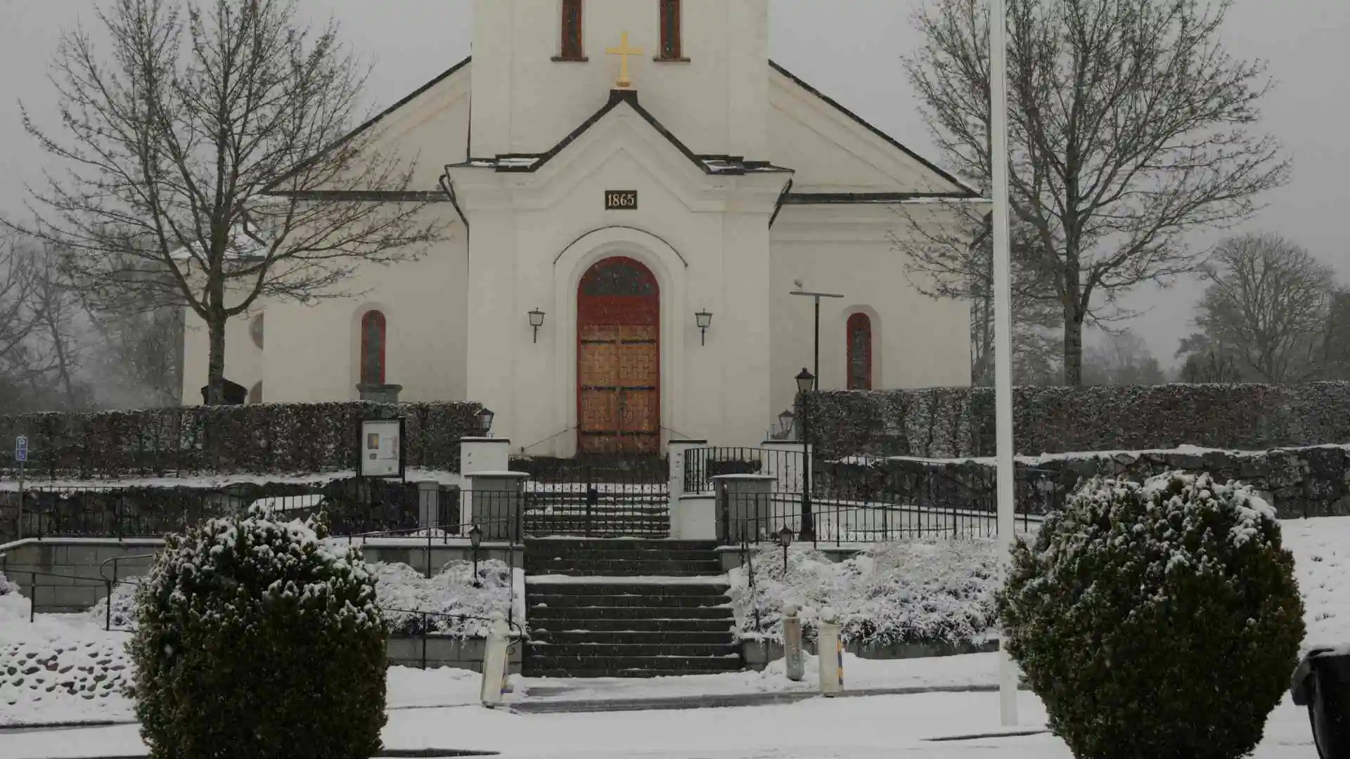 Bankeryds kyrka i vintermiljö med snö och träd runt entrén.
