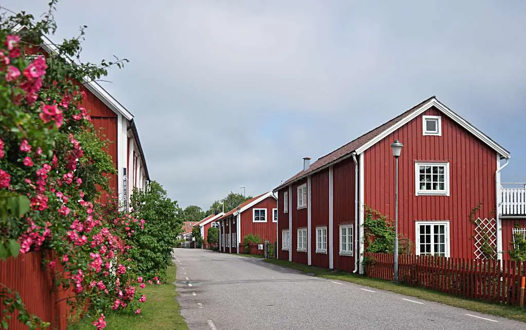 Röda träbyggnader längs grönskande bruksmiljö i Blekinge.