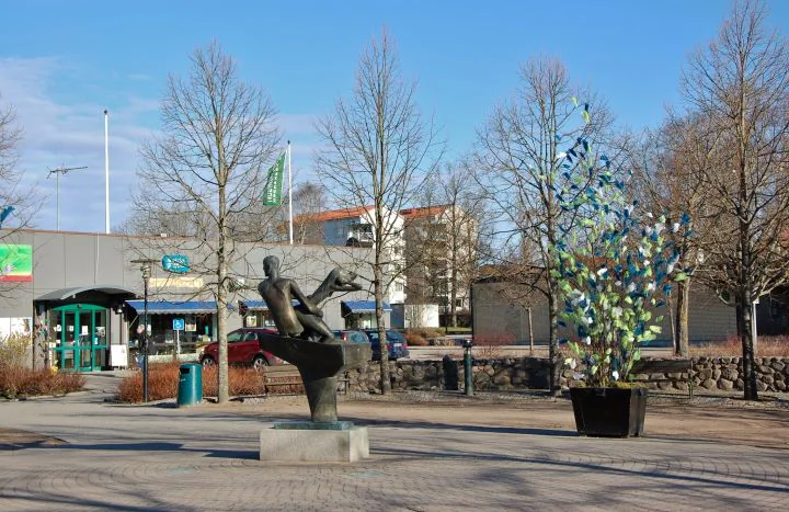 Torgmiljö i Emmaboda med konstverk, planteringar och låga centrumbyggnader.
