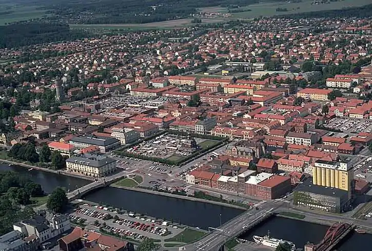 Flygvy över Lidköping med stadskvarter, hamnområde och Vänern.