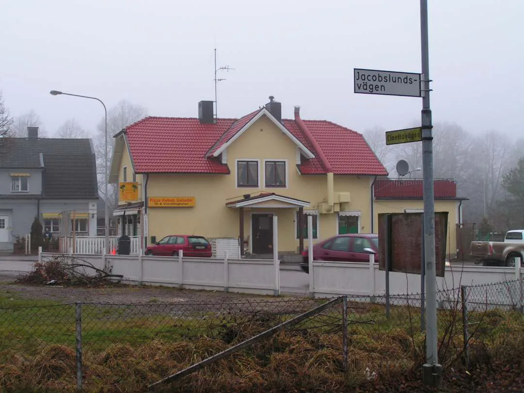 Herrgårdsbyggnad vid vatten i Ljungsbro med gröna träd och parkmiljö.