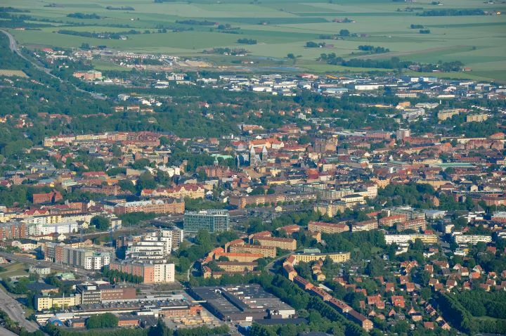 Flygvy över Lund med domkyrkans torn och tätt stadstak.