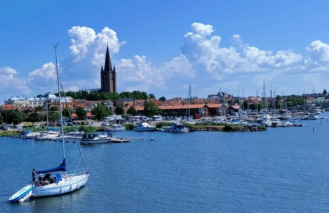 Mariestads hamn med segelbåtar, vatten och domkyrkotorn.