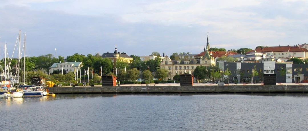 Oskarshamns hamn med segelbåtar, kaj och stadens bebyggelse.