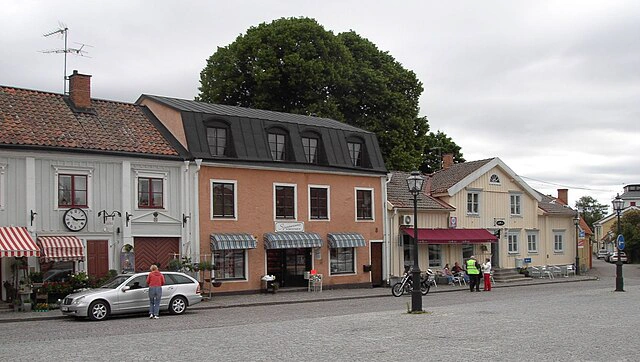 Skänninges småstadstorg med trähus, butiker och stenlagd gata.