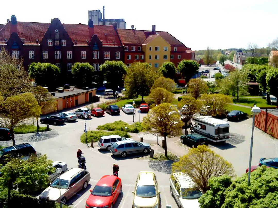 Centrumvy i Sölvesborg med gula byggnader, parkering och grönska.