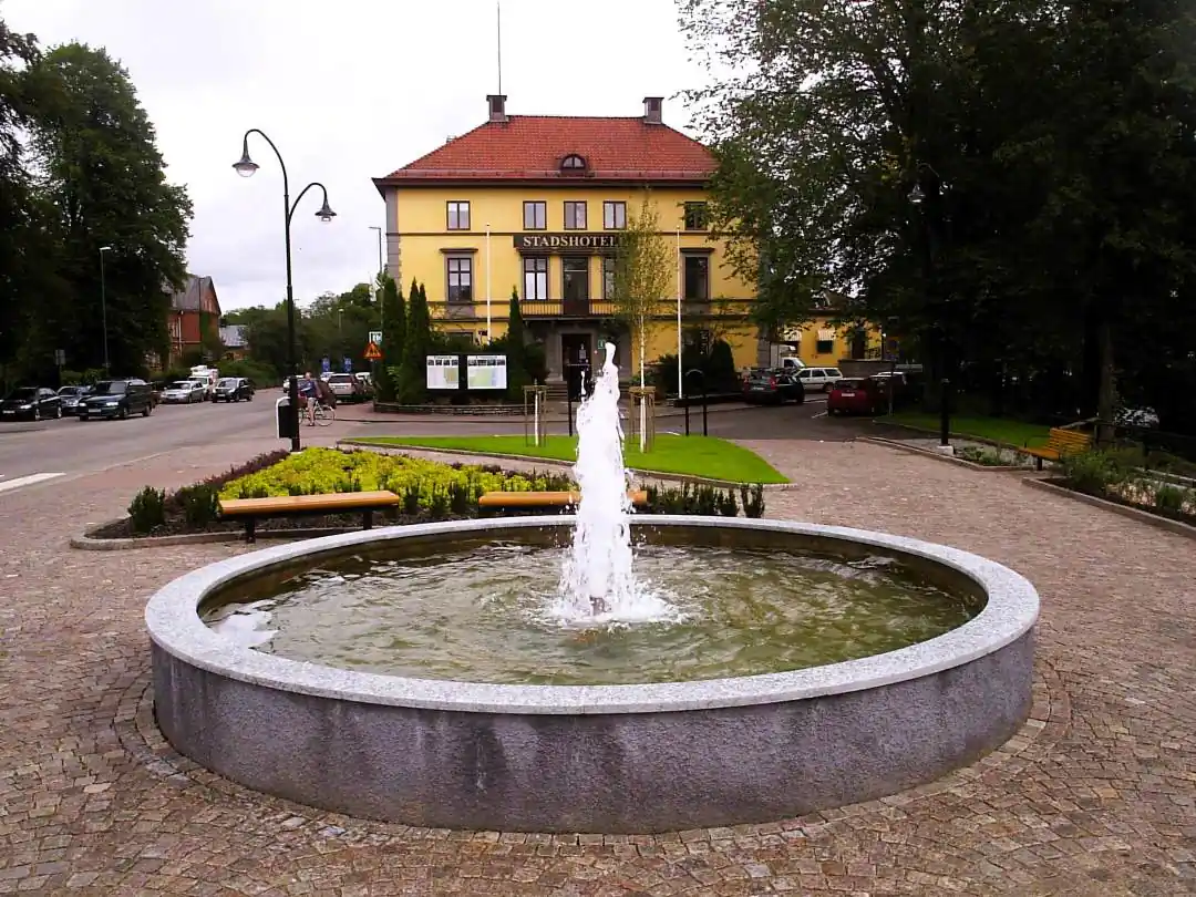 Fontän och gul stadshusmiljö i Tidaholm med torgyta framför.