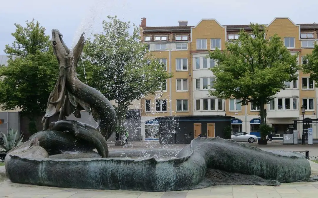 Torg i Trelleborg med fontän, skulptur och centrumhus.