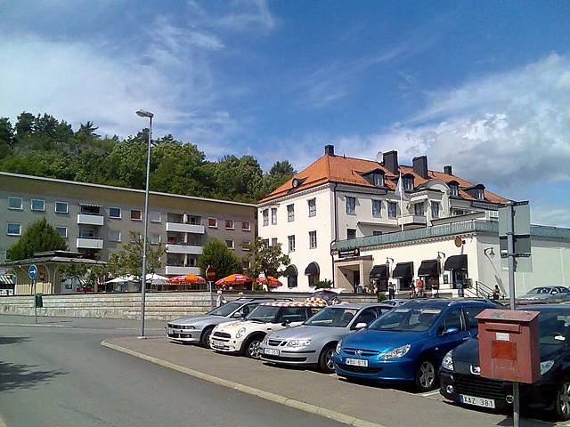 Centrumgata och parkerade bilar i Valdemarsvik med ljusa byggnader.