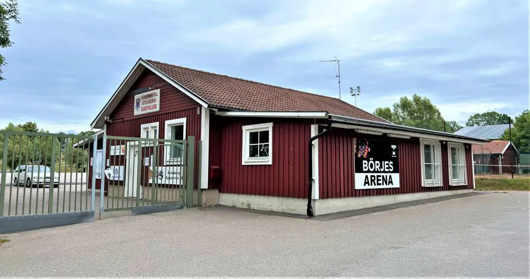 Röd träbyggnad i Åtvidaberg med takskylt och stationsliknande miljö.