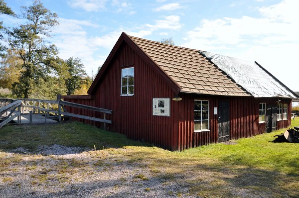 Rött trähus i Österbymo med tegeltak och frostig gård.